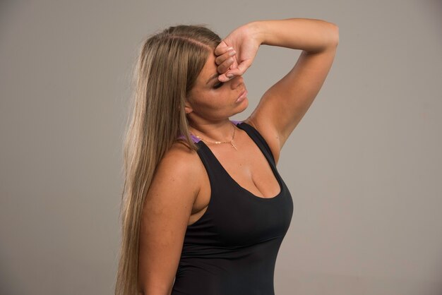 Free photo female model in sport bra puts hand to her forehead and looks tired, profile view.