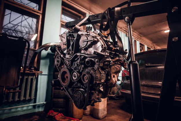 Female model with tattooed body wearing protective goggles next to a car engine