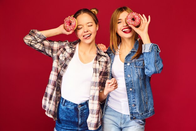 Female models holding pink donuts with sprinkles