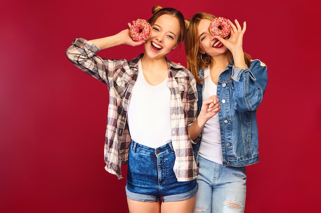 Modelli femminili in possesso di ciambelle rosa con spruzzi