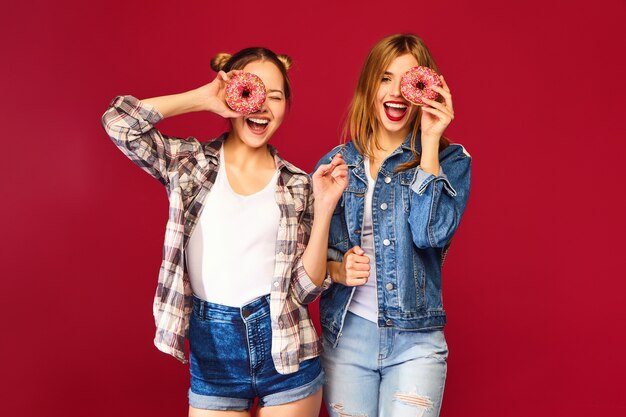 Female models holding pink donuts with sprinkles