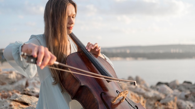 Бесплатное фото Женский музыкант играет на виолончели на закате с копией пространства