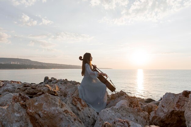 日没時に屋外でチェロを演奏する女性ミュージシャン