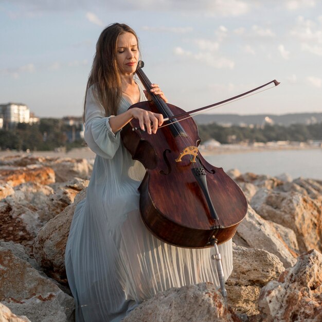 Female musician playing cello on rocks
