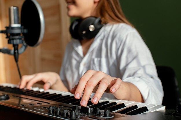 Female musician playing piano keyboard indoors and recording song