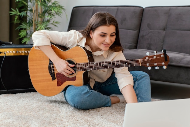 Female musician with acoustic guitar and laptop