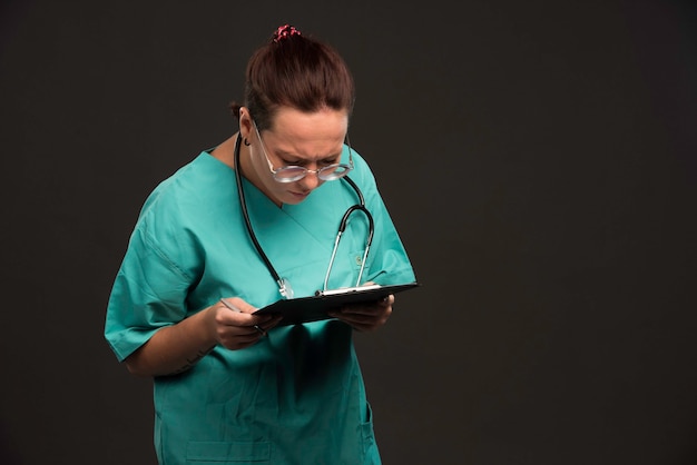 Медсестра в зеленой форме держит бланк и пытается читать.