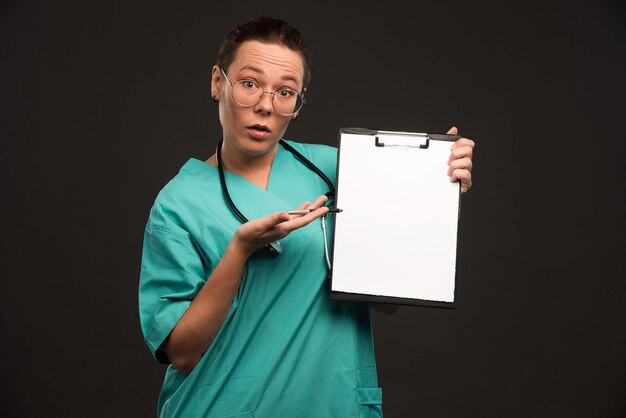 Female nurse in green uniform shows the history of the patient and making presentation.