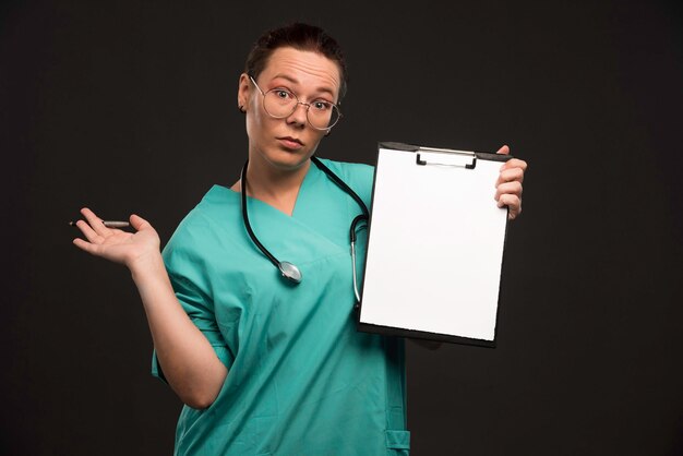 Female nurse in green uniform shows the history of the patient. 