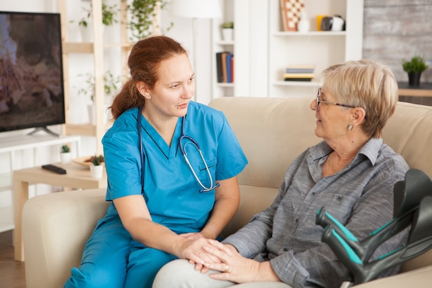 Female nurse having a conversation with pensioner woman in nursing home.