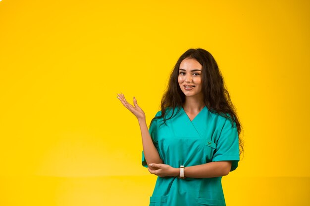 Female nurse opens hands and and points to something. 