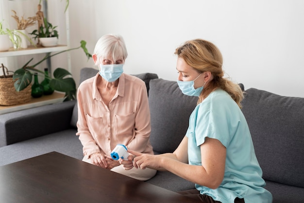 Female nurse showing older woman at nursing home the electronic thermometer