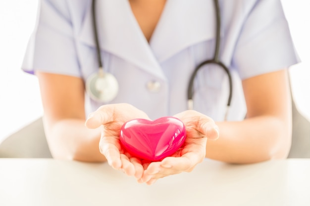 Бесплатное фото Женщина медсестра со стетоскопом держит сердце