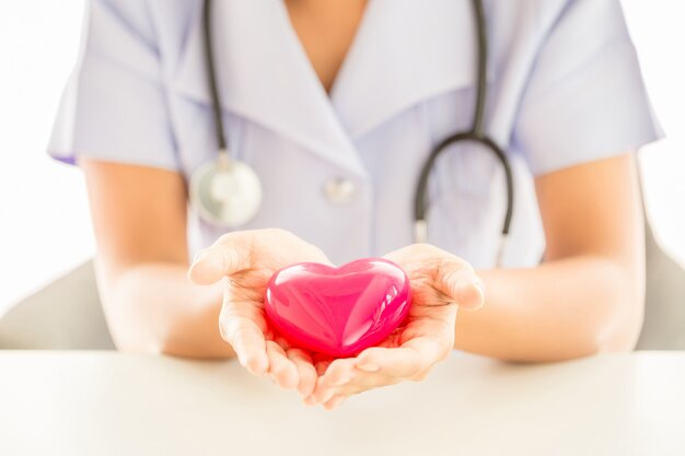 Женщина медсестра со стетоскопом держит сердце