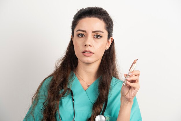 Female nurse with stethoscope holding thermometer.