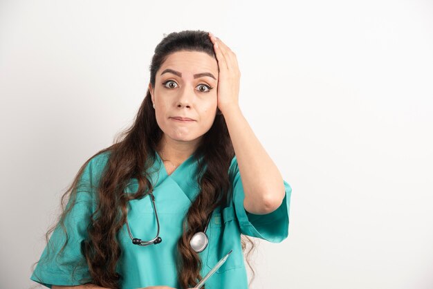 Female nurse with stethoscope holding thermometer.