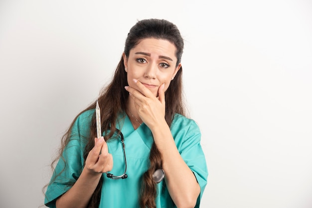 Free photo female nurse with stethoscope holding thermometer.