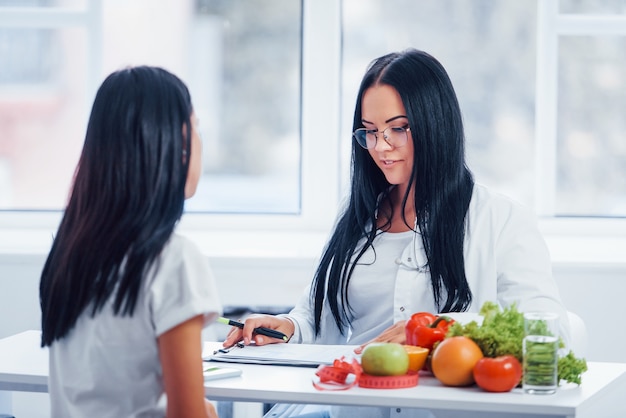 Female nutritionist gives consultation to patient indoors in the office. Premium Photo