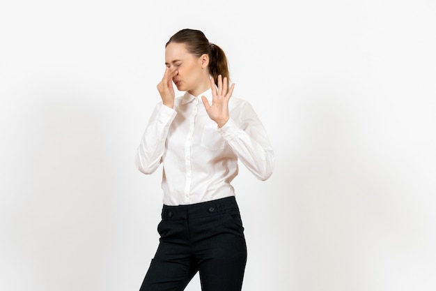 Free photo female office employee in elegant white blouse closing her nose on white