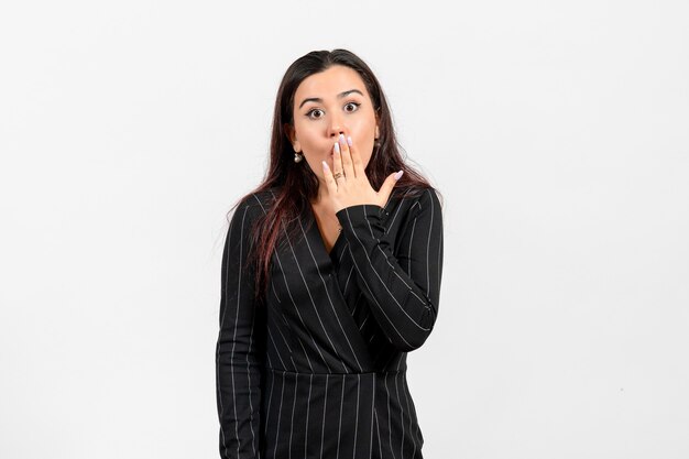 female office employee in strict black suit covering her mouth on white