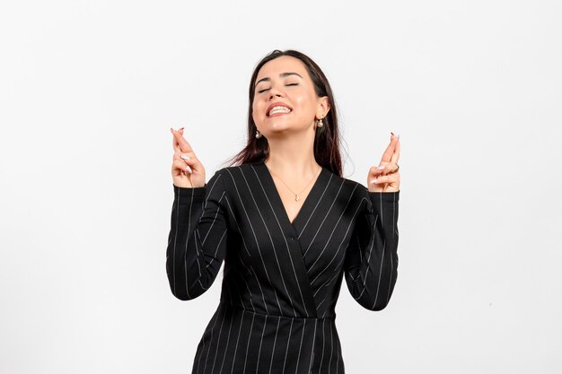 female office employee in strict black suit crossing her fingers on white