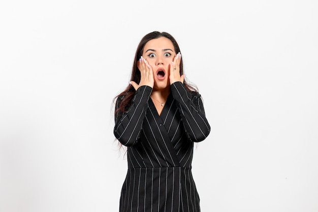 female office employee in strict black suit posing with shocked expression on white