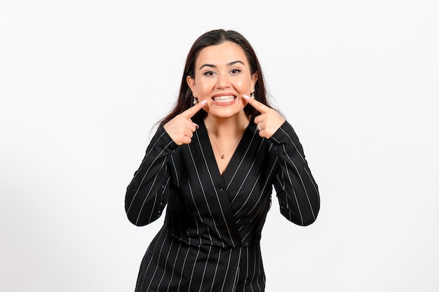 female office employee in strict black suit showing her teeth on white