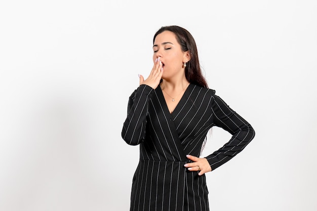 female office employee in strict black suit yawning on white