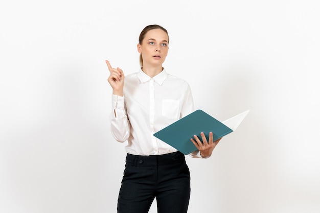 Impiegato femminile di ufficio in camicia bianca che tiene e che legge il file blu su bianco