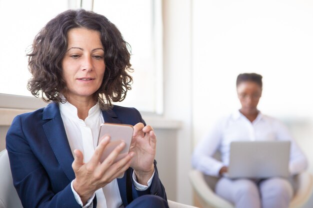 Female office employee with cell browsing web