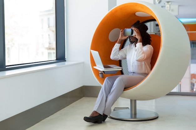 Free photo female office employee with laptop watching virtual presentation