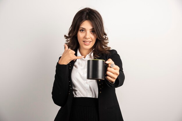 Female office worker offers a cup of tea and gesturing to call her