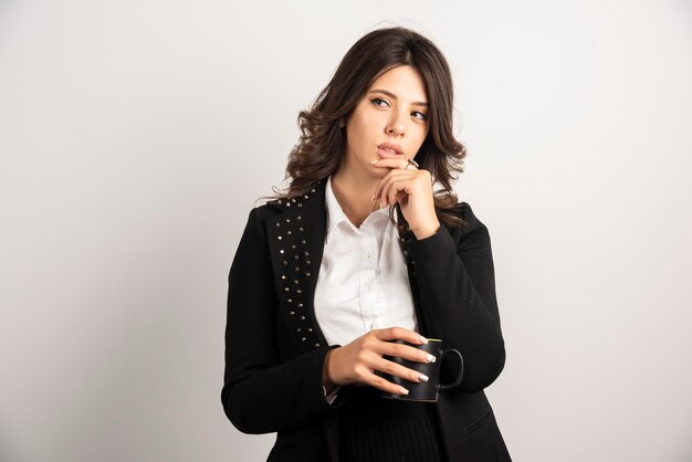 Female office worker posing with cup of tea on white