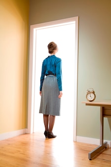 Female office worker standing in a doorway looking into a room illuminated ...