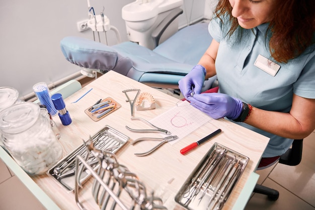 Женщина-ортодонт работает в стоматологическом кабинете