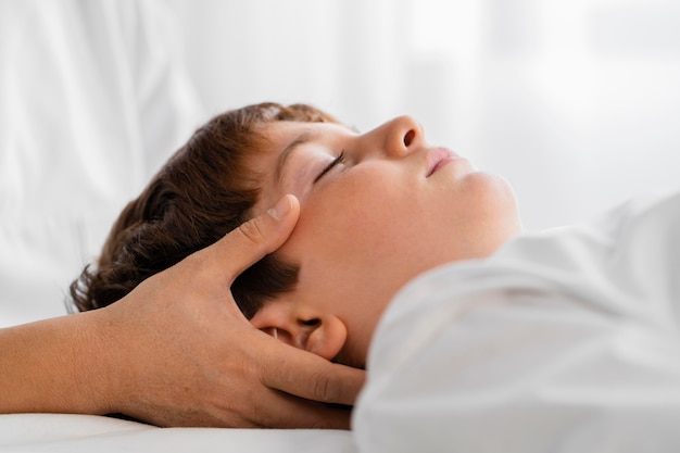 Female osteopathist treating a child by massaging his head