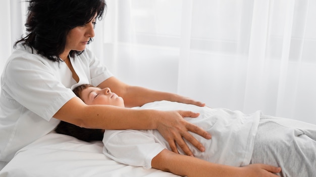 Женщина-остеопат лечит ребенка