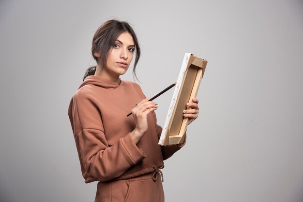 Female painter drawing on frame with brush