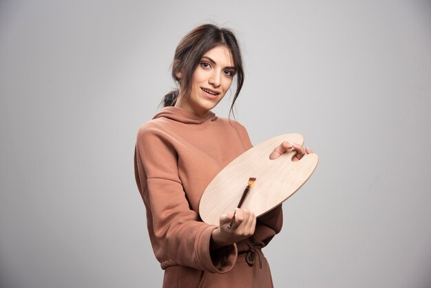 Female painter holding empty painter palette and brush