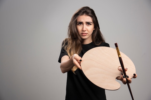 Female painter showing empty painter palette and brush. 