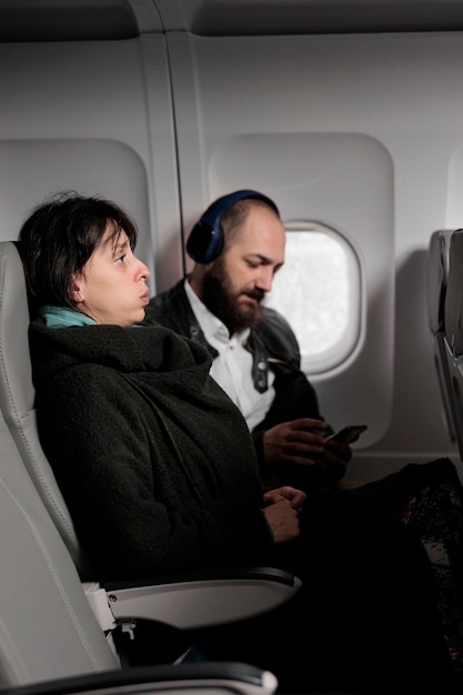 Женщина-пассажирка чувствует себя напряженной и напуганной взлетом самолета, боится летать за границу. Путешествие с международными авиалиниями, чтобы отправиться в отпуск, приключение, коммерческий рейс.