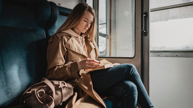 Foto gratuita lettura del passeggero femminile in una vista lunga del treno