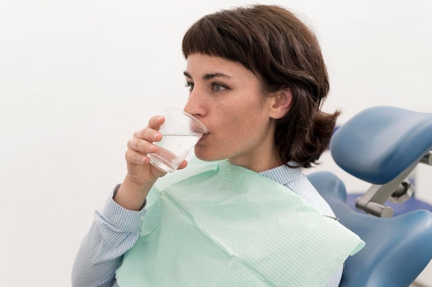 Female patient drinking water at the dentist office before dental procedure