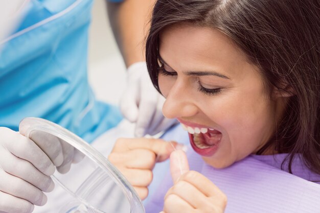 Женский пациент зубной нитью зубы