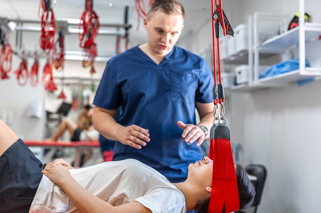 Free photo female patient hanging on suspensions at rehabilitation center