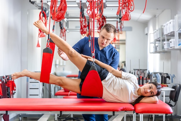 Free photo female patient hanging on suspensions at rehabilitation center