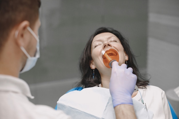Пациентка проходит стоматологическое обследование в кабинете стоматолога. Женщина брюнетка