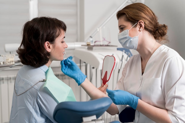 Пациентка смотрит в зеркало в кабинете стоматолога