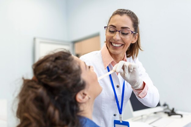 Female patient opening her mouth for the doctor to look in her throat Otolaryngologist examines sore throat of patient