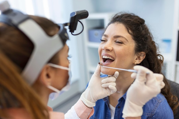 Female patient opening her mouth for the doctor to look in her throat Otolaryngologist examines sore throat of patient